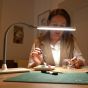 Daylight Company UnoPro Table Lamp - lifestyle shot, using the lamp to do crafting